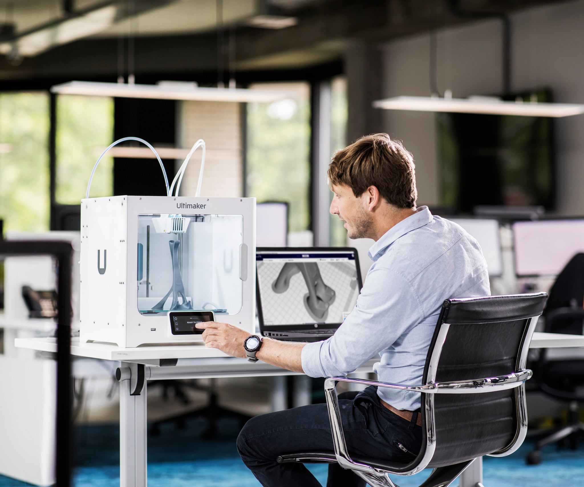 man sat at desk with laptop and UltiMaker S3 3D printer